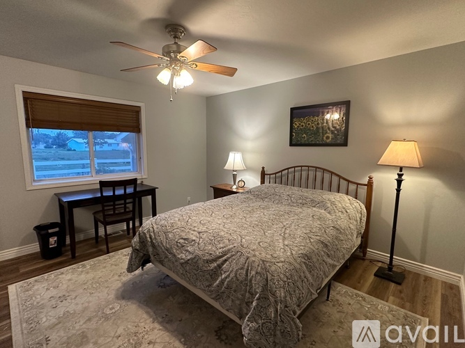 A bedroom with a bed, desk, and window.