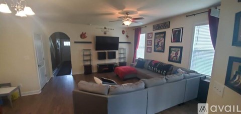 A living room with a grey couch and a television on the wall.