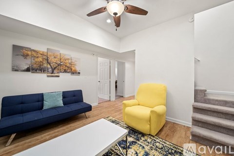 A living room with a blue couch, yellow chair, and a white coffee table.