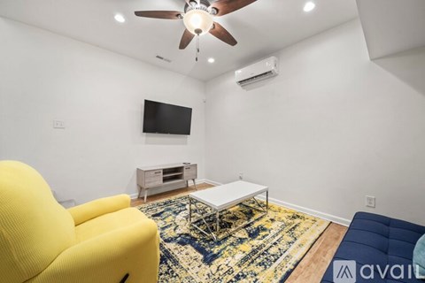 A living room with a yellow chair, a white coffee table, and a blue couch.