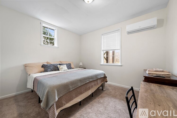 A bedroom with a bed, chair, and window.