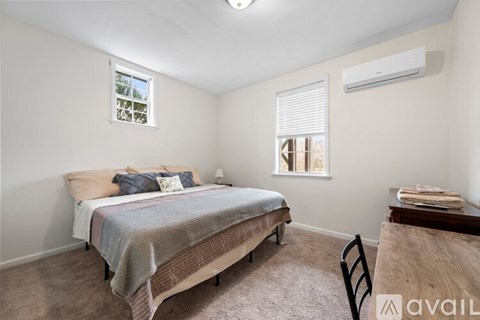 A bedroom with a bed, chair, and window.