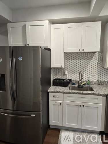 A kitchen with a stainless steel refrigerator and white cabinets.
