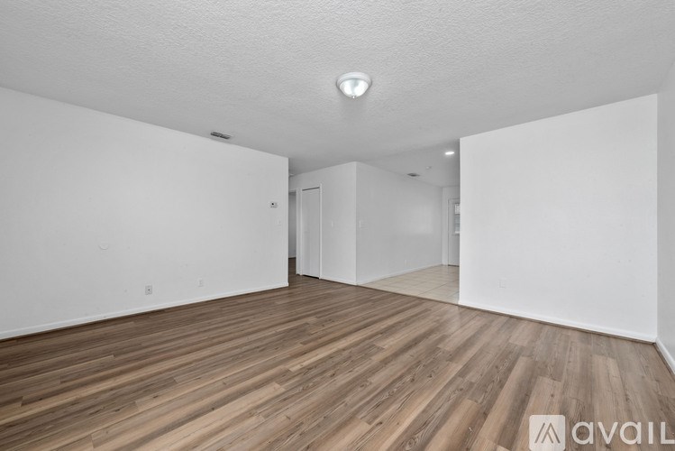 A spacious room with wooden flooring and white walls.