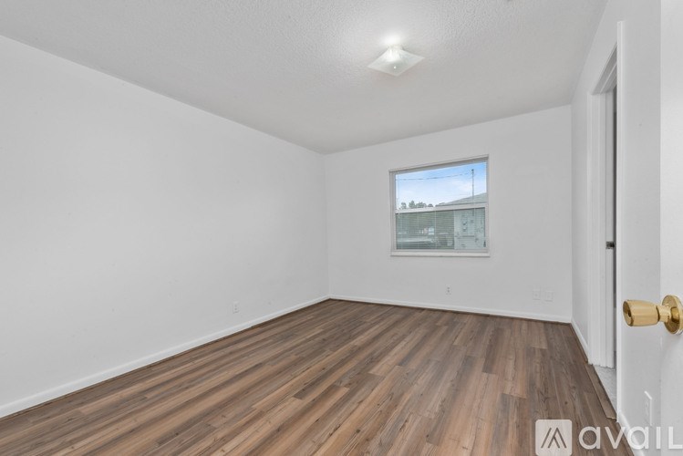 A room with wooden flooring and a window showing a building outside.