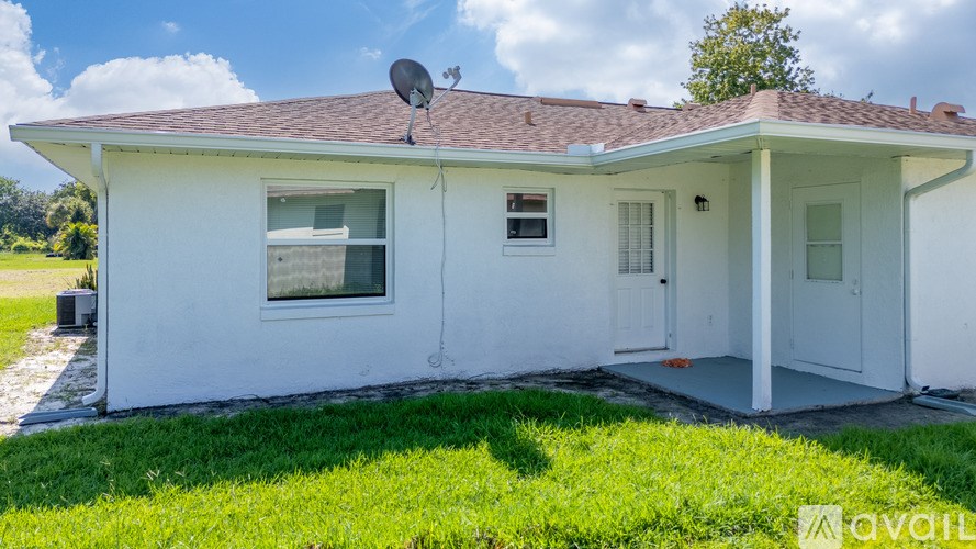 A white house with a brown roof and a satellite dish on the roof.