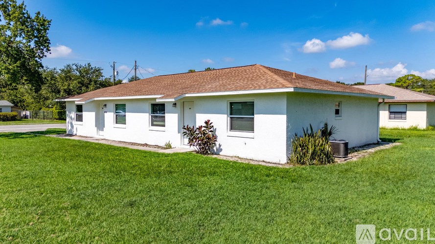 A white house with a brown roof is for sale.
