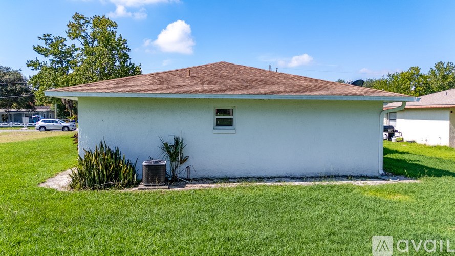 A small white building with a brown roof is surrounded by a grassy area.