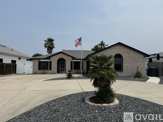 A house with a palm tree in front and an American flag on top.