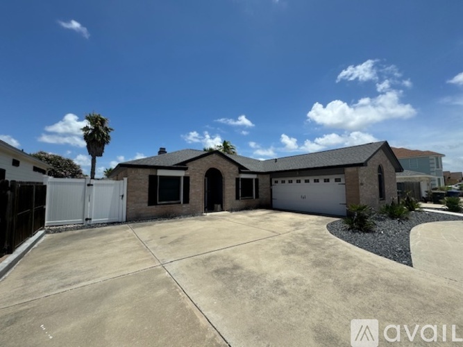 A house with a driveway and a palm tree in front.