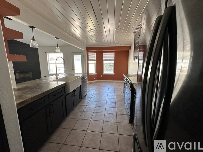 A modern kitchen with black cabinets and a large refrigerator.