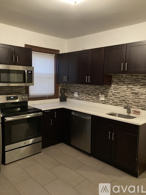 A kitchen with dark brown cabinets and a white countertop.