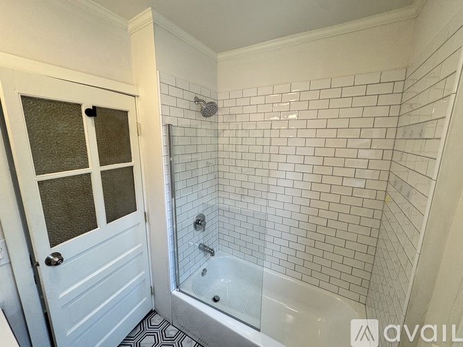 A white door with a glass window is next to a white tiled shower.