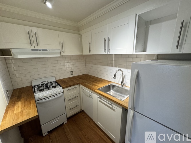 A kitchen with white cabinets and a wooden countertop.