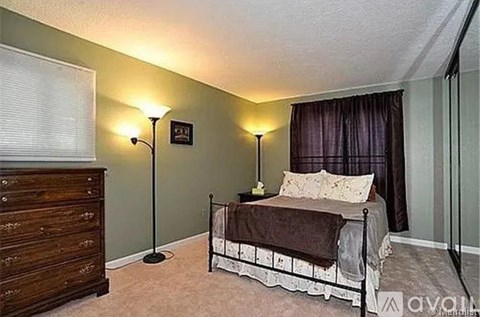 A bedroom with a bed, nightstand, and lamp.