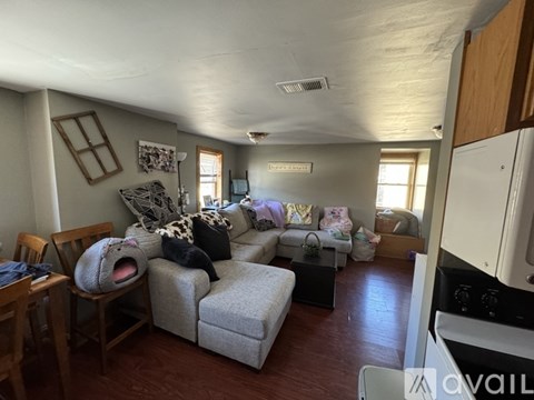 A living room with a grey couch and a grey blanket on it.