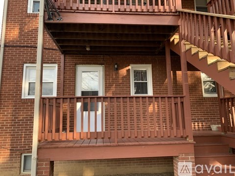 A red brick building with a wooden balcony and stairs.