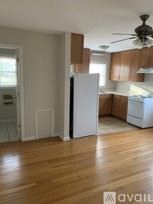 A kitchen with a white refrigerator and wooden floors.