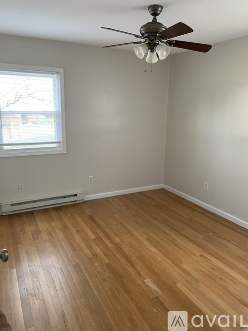 A room with a ceiling fan and wooden flooring.