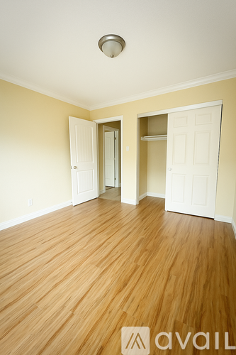 A room with wooden floors and two open doors.