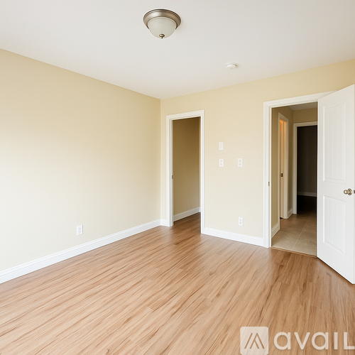 A room with wooden floors and two open doors.