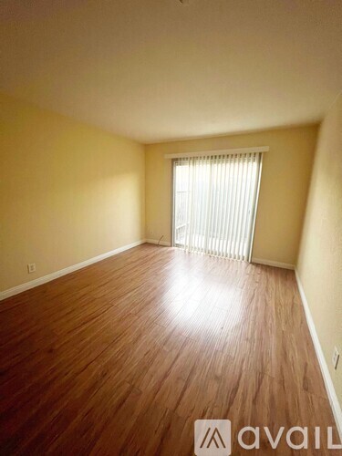A room with wooden flooring and a window with blinds.