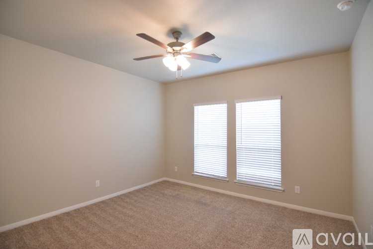 A spacious room with a ceiling fan and a single window with blinds.