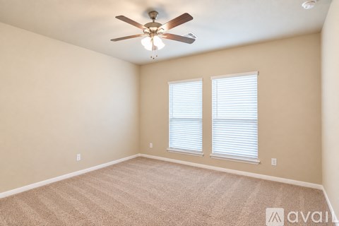 A spacious room with a ceiling fan and a single window with blinds.