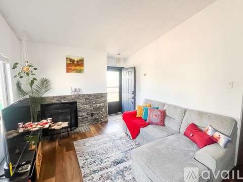 A living room with a grey couch and a stone fireplace.