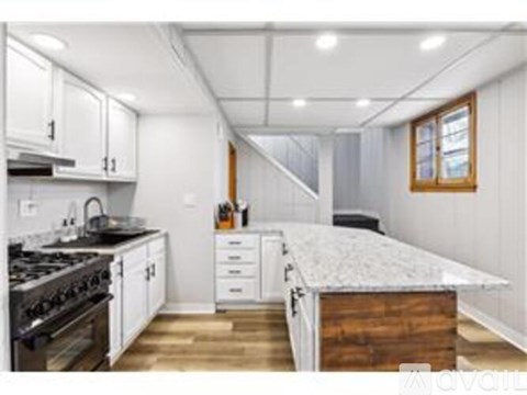 A kitchen with white cabinets and a wooden island.