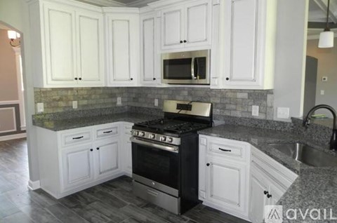 A kitchen with white cabinets and a black stove top oven.
