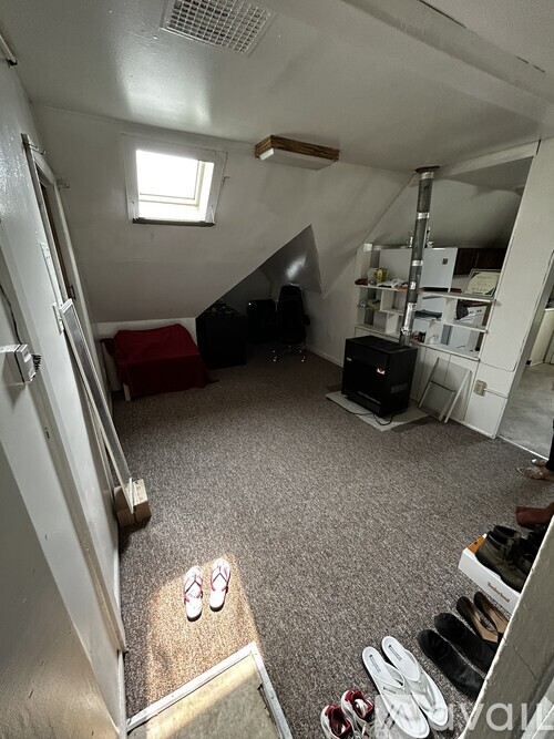 A pair of white flip flops are on the floor of a room with a window.