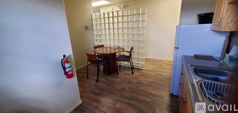 A kitchen area with a table and chairs and a fridge.