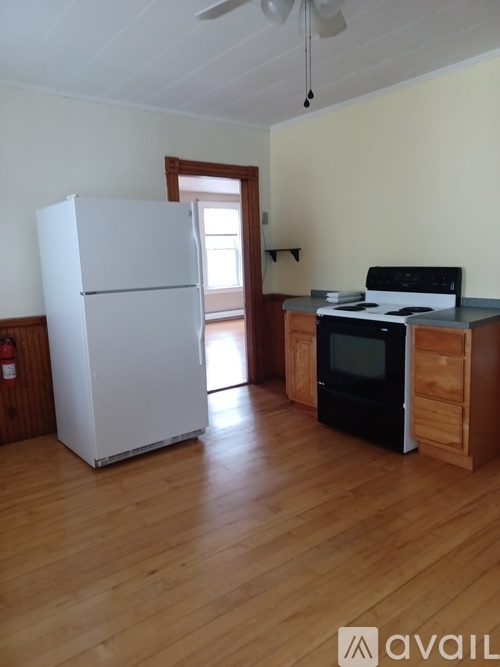 A white refrigerator is in a kitchen with a black microwave.