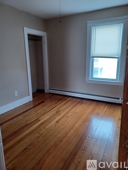 A room with wooden floors and a window with blinds.