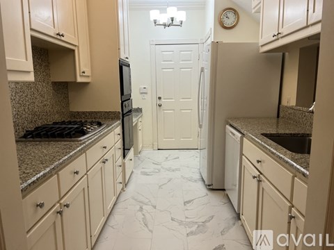 A kitchen with a white refrigerator and a marble floor.