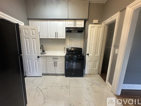 A kitchen with white cabinets and a black fridge.