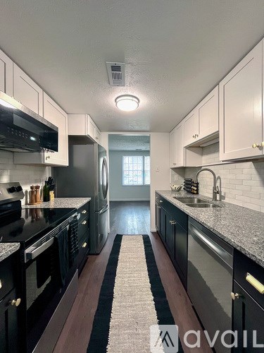 A kitchen with black appliances and white cabinets.