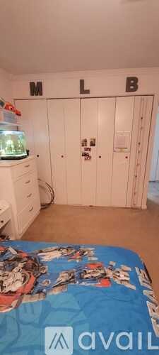 A bedroom with a bed and a white wardrobe with the letters MLB on it.