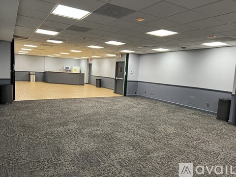A large, empty room with grey carpeting and white walls.