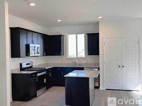 A kitchen with black cabinets and a white door.