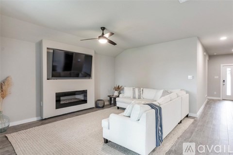 A living room with a white couch and a television mounted above a fireplace.