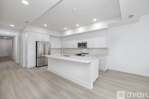 A kitchen with white cabinets and a white island with a microwave on top.