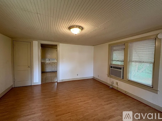 A room with wooden floors and a window with blinds.