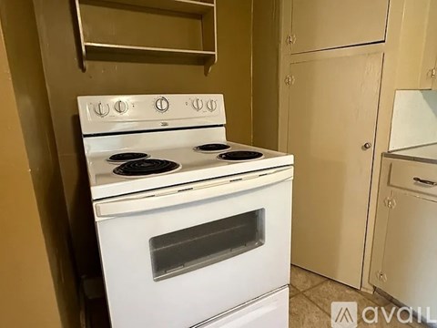 A white stove with four burners and an oven is in a kitchen.