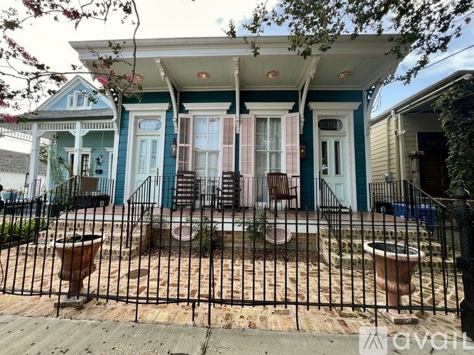 A blue house with a black fence and a small garden in front.