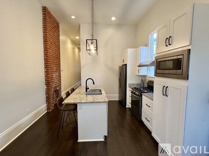 A kitchen with white cabinets and a brick wall.