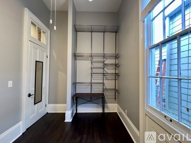 A room with a white door, a table, and a window with a view of a building outside.