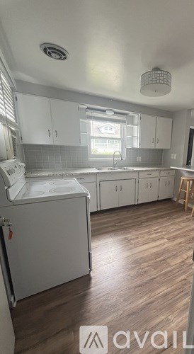 A kitchen with white cabinets and a wooden floor.