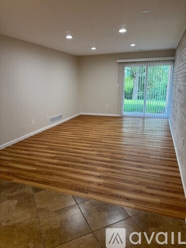 A room with wooden flooring and a sliding glass door leading to a garden.